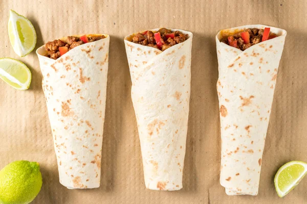 Zöldséges marhahús egy papírra ízletes házi készítésű burrito. — Stock Fotó