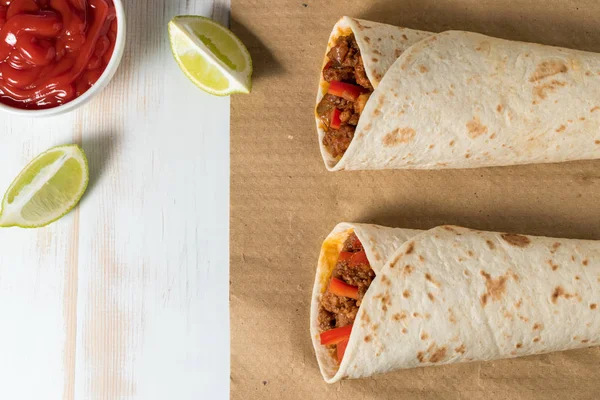 Leckeres hausgemachtes Burrito mit Gemüse und Rindfleisch auf Papier. — Stockfoto