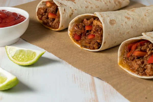 Leckeres hausgemachtes Burrito mit Gemüse und Rindfleisch auf Papier. — Stockfoto