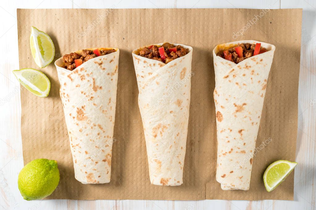 Tasty homemade burrito with vegetables and beef on a paper.
