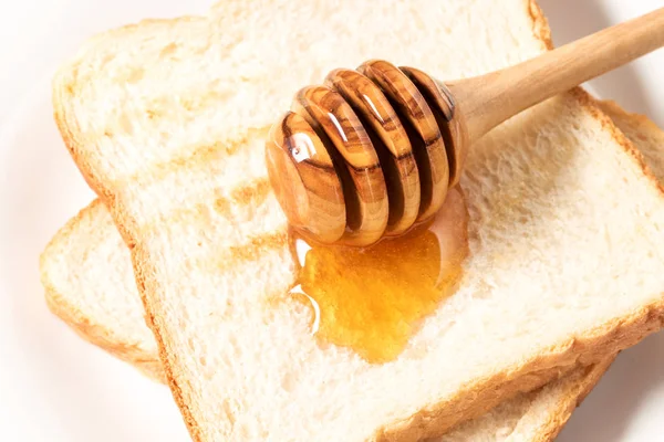 Μέλι με ραβδί ρίχνει πάνω από ψωμί τοστ — Φωτογραφία Αρχείου