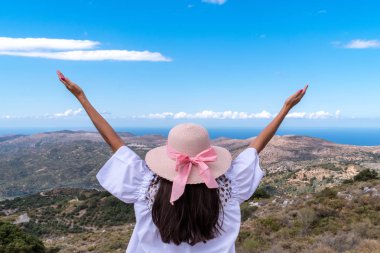 Geniş şapka ve dağlar ve deniz arka plan karşı elleri ile kız