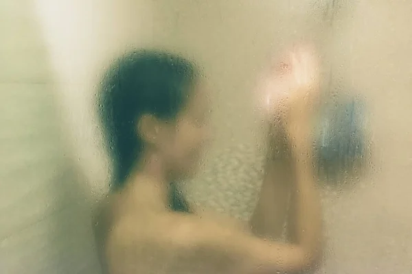 Beautiful woman in the shower behind glass with drops. Green glow — Stock Photo, Image