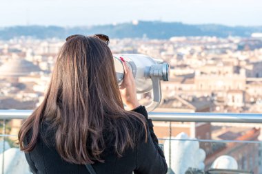 Kadın turist şehir yüksek bir noktada Roma'dan üzerinde dürbün üzerinden arıyor.