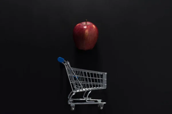 Apple y carrito de compras sobre fondo negro . — Foto de Stock