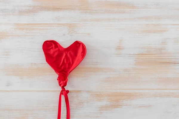 Ballon en forme de coeur dégonflé sur fond blanc en bois montrant — Photo