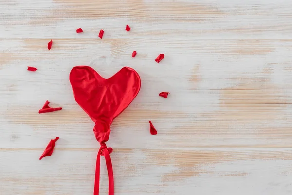 Leeggelopen hart vorm ballon op witte houten achtergrond — Stockfoto