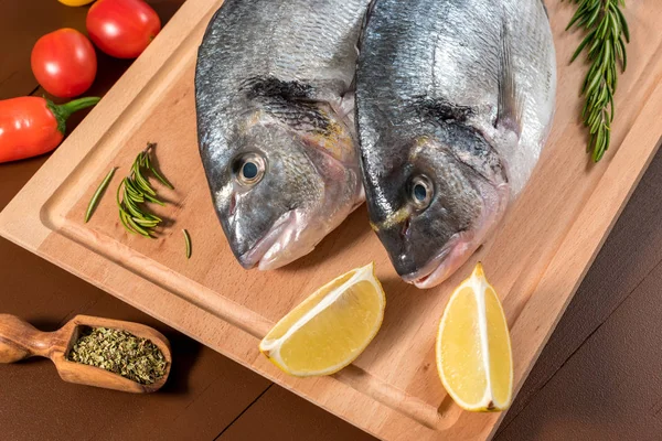 Fresh uncooked dorado or sea bream fish with lemon, herbs, vegetables and spices — Stock Photo, Image