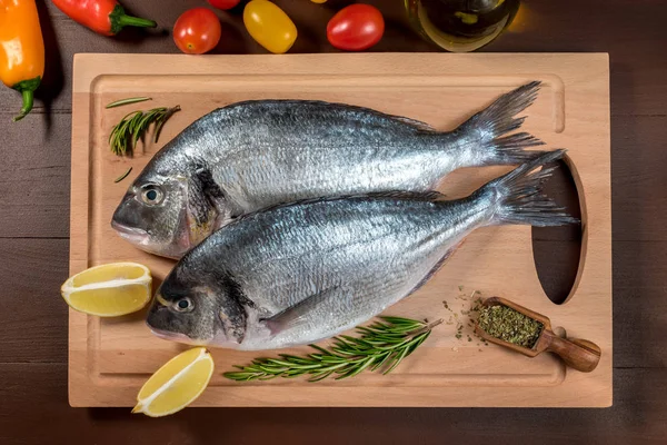 Fresh uncooked dorado or sea bream fish with lemon, herbs, oil, vegetables and spices — Stock Photo, Image