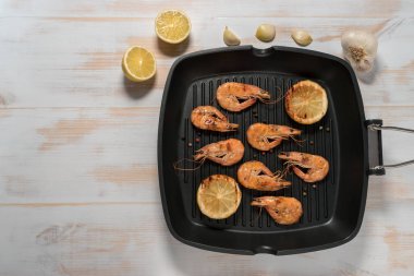 Limon, kırmızı biber, baharatlar ve otlar ile ızgara tava üzerinde ızgara karides.