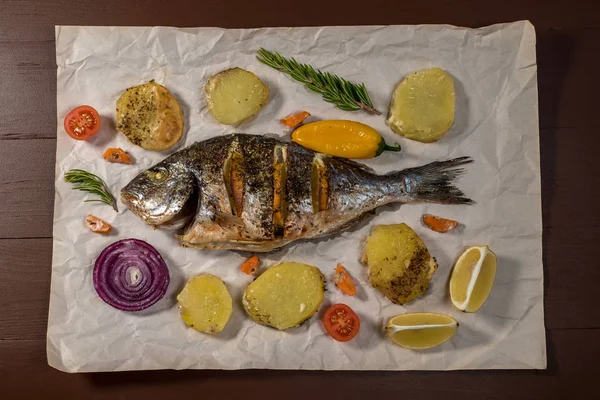 Tasty baked whole fish on baking paper. Baked sea bream with lemon — Stock Photo, Image