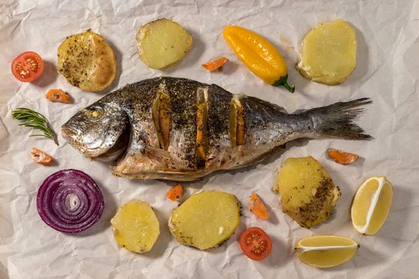 Tasty baked whole fish on baking paper. Baked sea bream with lemon — Stock Photo, Image
