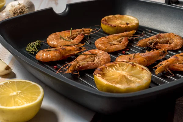 Grilled shrimp on a grill frying pan with lemon, paprika, spices and herbs.