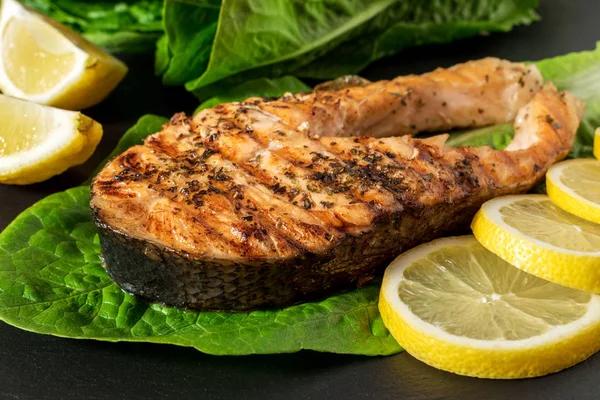 Salmon fillet. Grilled salmon with herb and lemon on black slate board.