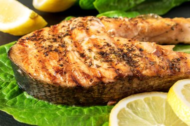 Somon fileto. Ot ve siyah arduvaz tahta üzerinde limon ile ızgara somon. 