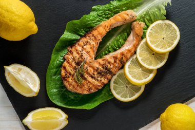 Somon fileto. Ot ve siyah arduvaz tahta üzerinde limon ile ızgara somon