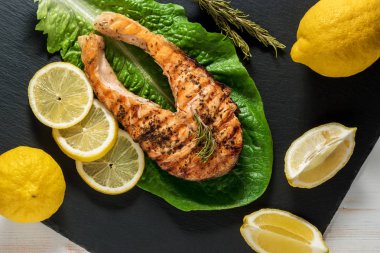 Somon fileto. Ot ve siyah arduvaz tahta üzerinde limon ile ızgara somon