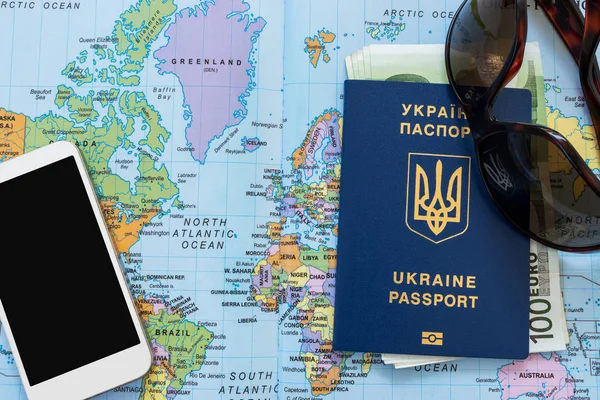 Ukraiński paszport na mapie świata. Banknoty euro, Okulary przeciwsłoneczne i telefon komórkowy na tle. — Zdjęcie stockowe