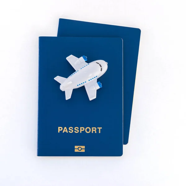 Piccolo aereo giocattolo in cima a passaporti blu su uno sfondo bianco . — Foto Stock