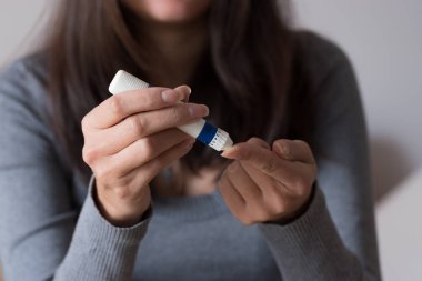 Kadın el lancet şekeri ölçüm cihazı tarafından kan şeker seviyesini kontrol etmek için parmağına kullanarak yakın çekim. 