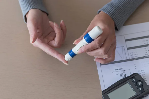 血糖値計で血糖値をチェックする指にランセットを使用して女性の手のクローズ アップ. — ストック写真