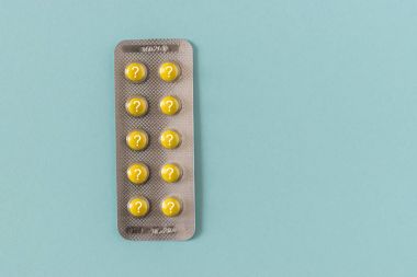 Sarı soru işareti mavi zemin üzerine haplarla.