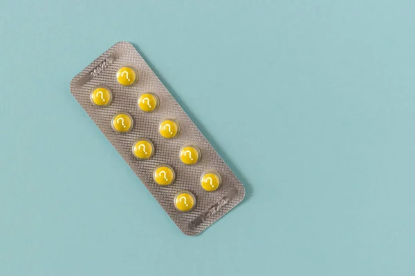 Pillole gialle con punto interrogativo su sfondo blu . — Foto Stock