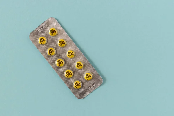 Επικίνδυνα κίτρινο χάπια με το λογότυπο του κρανίου σε μπλε φόντο. — Φωτογραφία Αρχείου