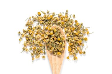 Beyaz arka plan üzerine bir kaşık kuru papatya çayı.