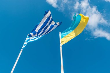 Mavi gökyüzü arka plan üzerinde Yunan bayrağı ile Ukrayna bayrağı