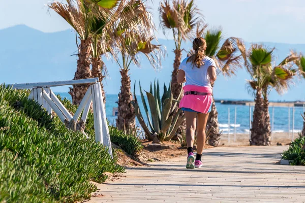 Sporty woman jogging near to the beach, young girl in sporty clo