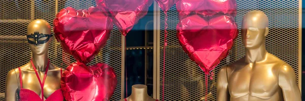 Mostra festiva em uma loja com manequins de ouro e balões em forma de coração . — Fotografia de Stock