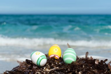 Güneşli bir gün sahilde renkli Paskalya yumurtaları.