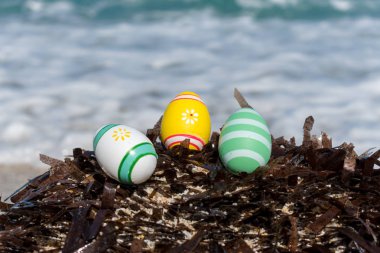 Güneşli bir gün sahilde renkli Paskalya yumurtaları.