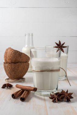 Hindistan cevizi ve Hindistan cevizi sütü cam ile ahşap masa üzerinde tarçın kabuğu