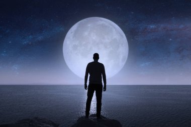 A man looks at the stars and the moon.   clipart