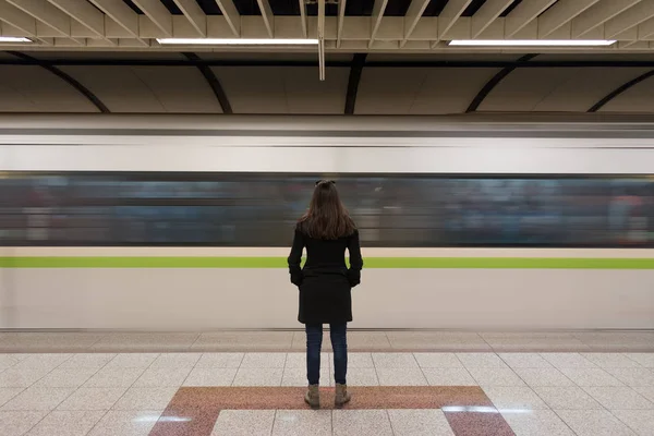 Mujer joven con abrigo negro en la plataforma subterránea — Foto de Stock