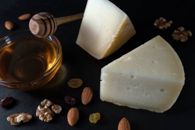 Yunan peynir graviera ve bir dilim fındık, bal ve otlar ile siyah taş gemide.