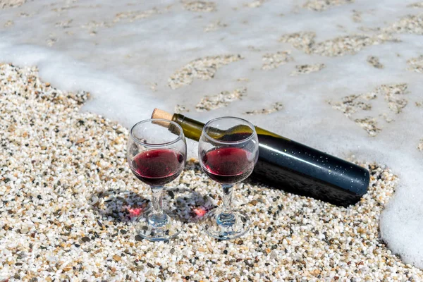 Glazen rode wijn en een fles op het strand bij het zonnige zomerdag — Stockfoto