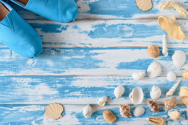 Seashells su tavola di legno blu con scarpe estive. Estate sfondo vacanza . — Foto Stock