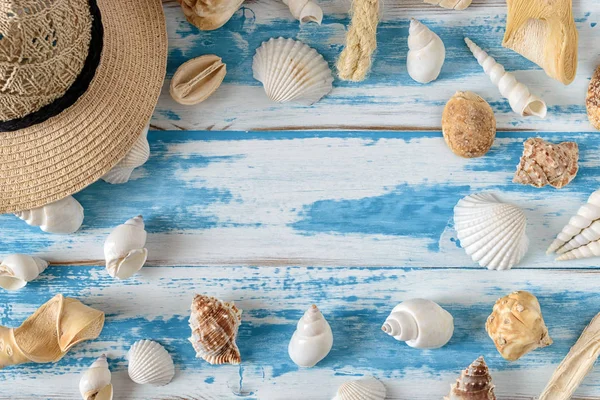 Seashells su tavola di legno blu con cappello di paglia . — Foto Stock