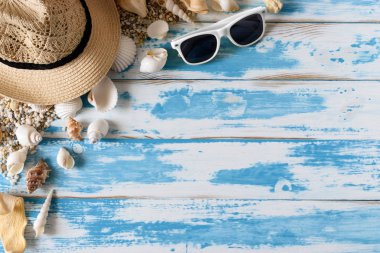 Hasır şapka ve güneş gözlüğü ile mavi ahşap tahta üzerinde deniz kabuklarını. Yaz tatil arka plan.