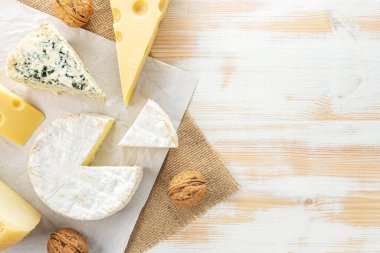 Beyaz ahşap masada değişik peynir çeşitleri var. Peynir arkaplanı.