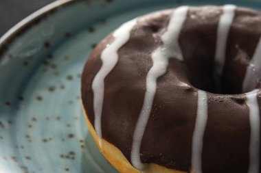 Siyah bir masada mavi bir tabakta çikolatalı çörek. Yakın plan..
