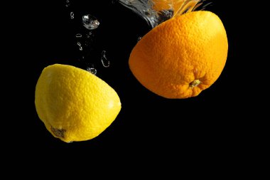 Siyah arka planda taze dilimlenmiş portakal ve limon. En az gıda konsepti.