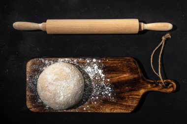 Ekmek için taze çiğ hamur ya da un tozlu, ahşap bir arka planda pizza. Üst görünüm.