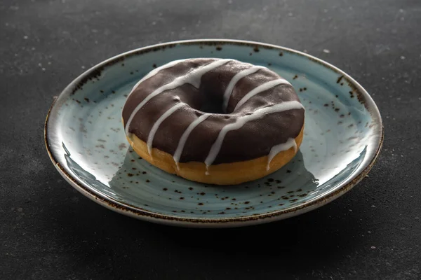 Donut Com Chocolate Uma Chapa Azul Uma Mesa Preta Close — Fotografia de Stock