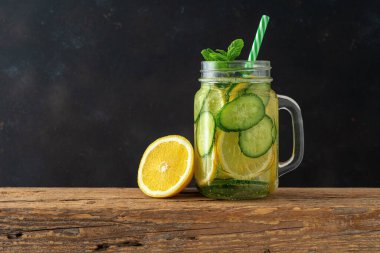 Koyu arkaplanda dilimlenmiş limon ve salatalıkla detoks suyu. Sağlıklı konsept.