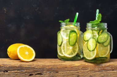 Koyu arkaplanda dilimlenmiş limon ve salatalıkla detoks suyu. Sağlıklı konsept.