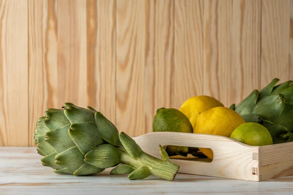 Mogna Ekologiska Kronärtskockor Ett Vitt Träbord Med Citron Vegetabilisk Bakgrund — Stockfoto